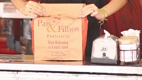 Saco kraft com o logo Pai & Filhos e Disk Delivery sendo embalado